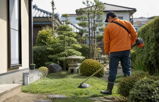 住宅の庭で草刈りを行う作業イメージ